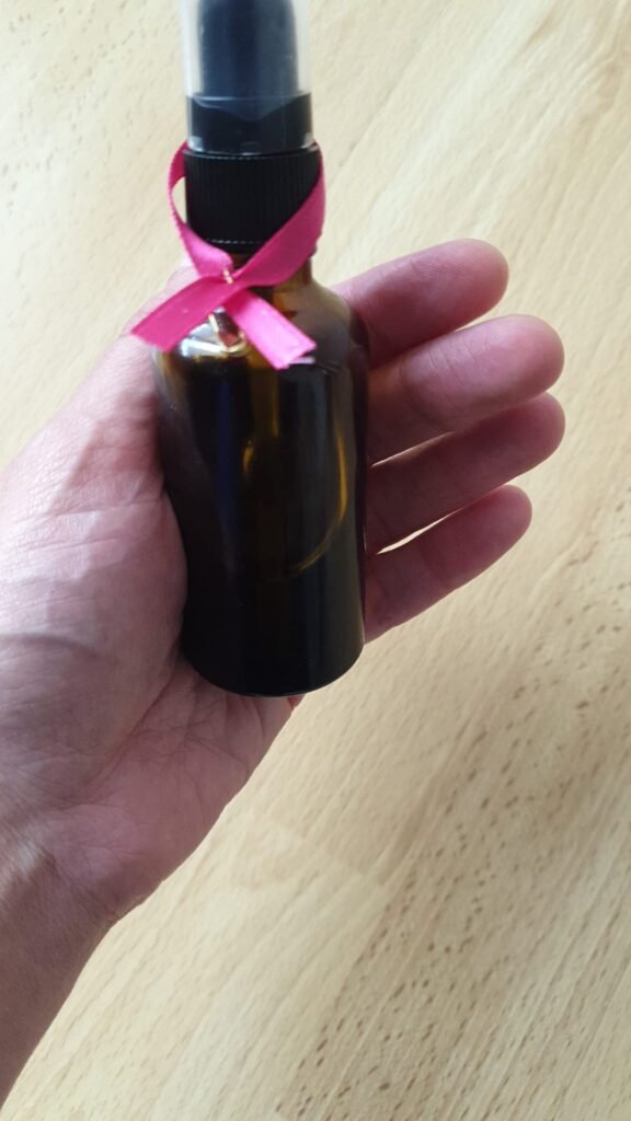 Flacon d'huile de massage bien-être orné d'un ruban rose Octobre Rose à Talensac